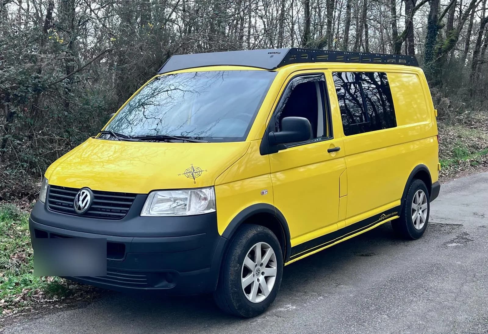 Volkswagen T5 amarilla con el rack WRX4, aparcada junto a un bosque