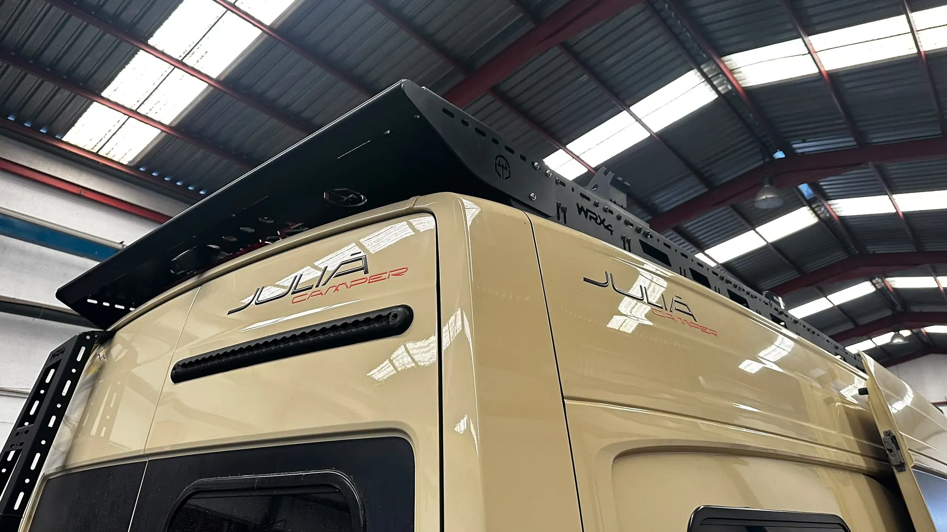 Trasera de una camper MAN beige con la visera trasera WRX4, el rack y la escalera